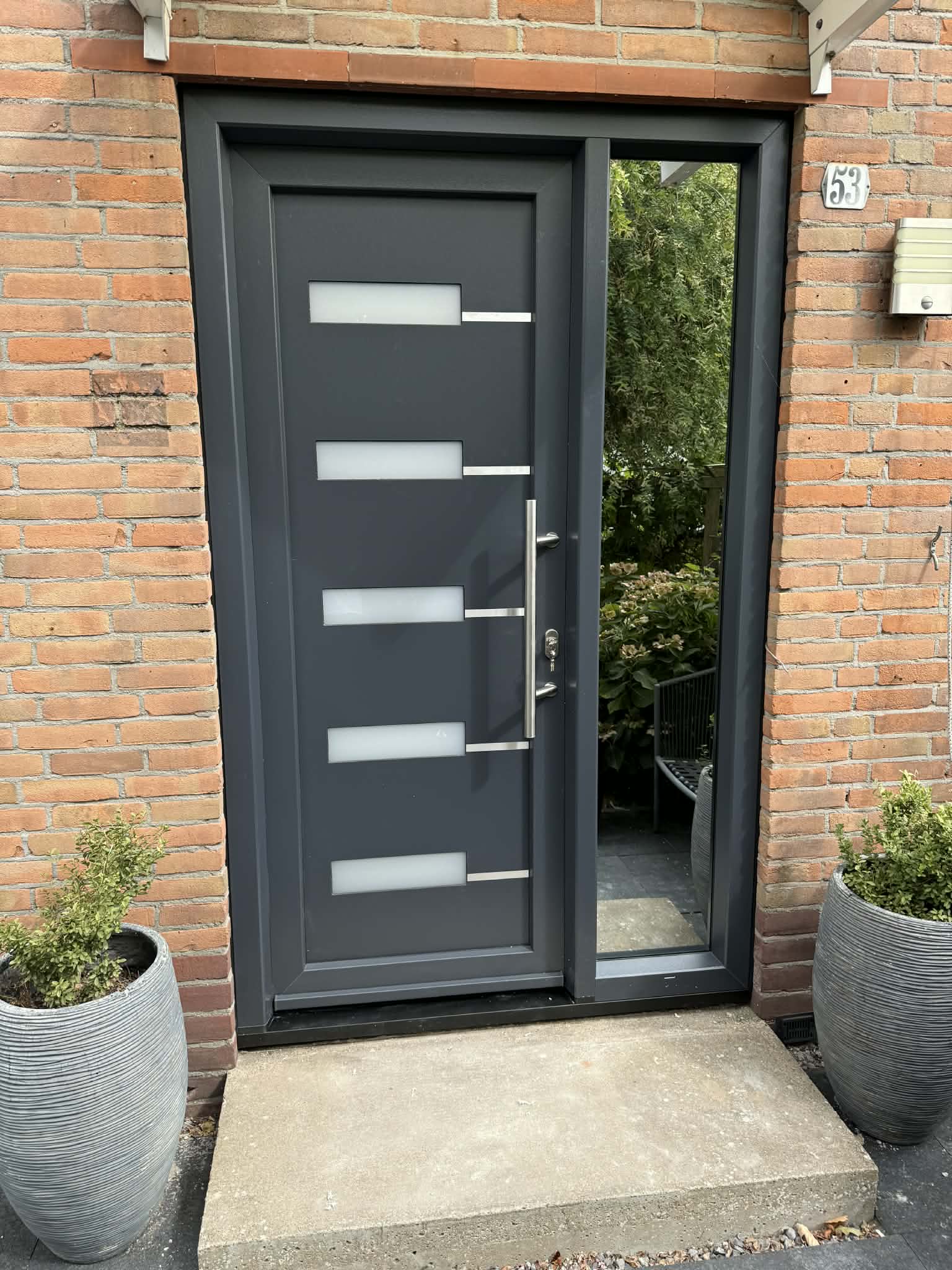 Antracietkleurige voordeur met vijf glasstroken en zijlicht