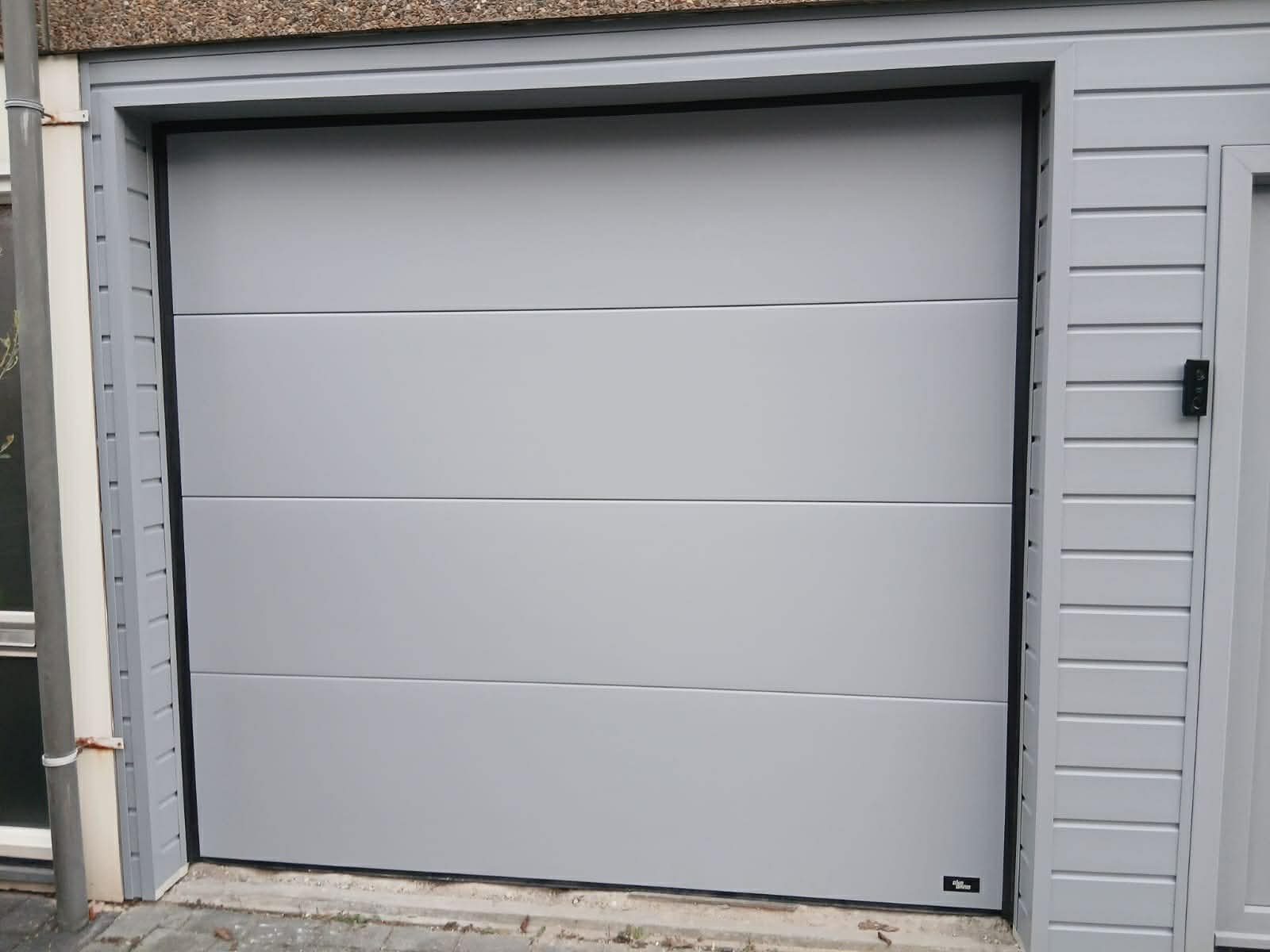 Moderne lichtgrijze sectionaaldeur voor een garage