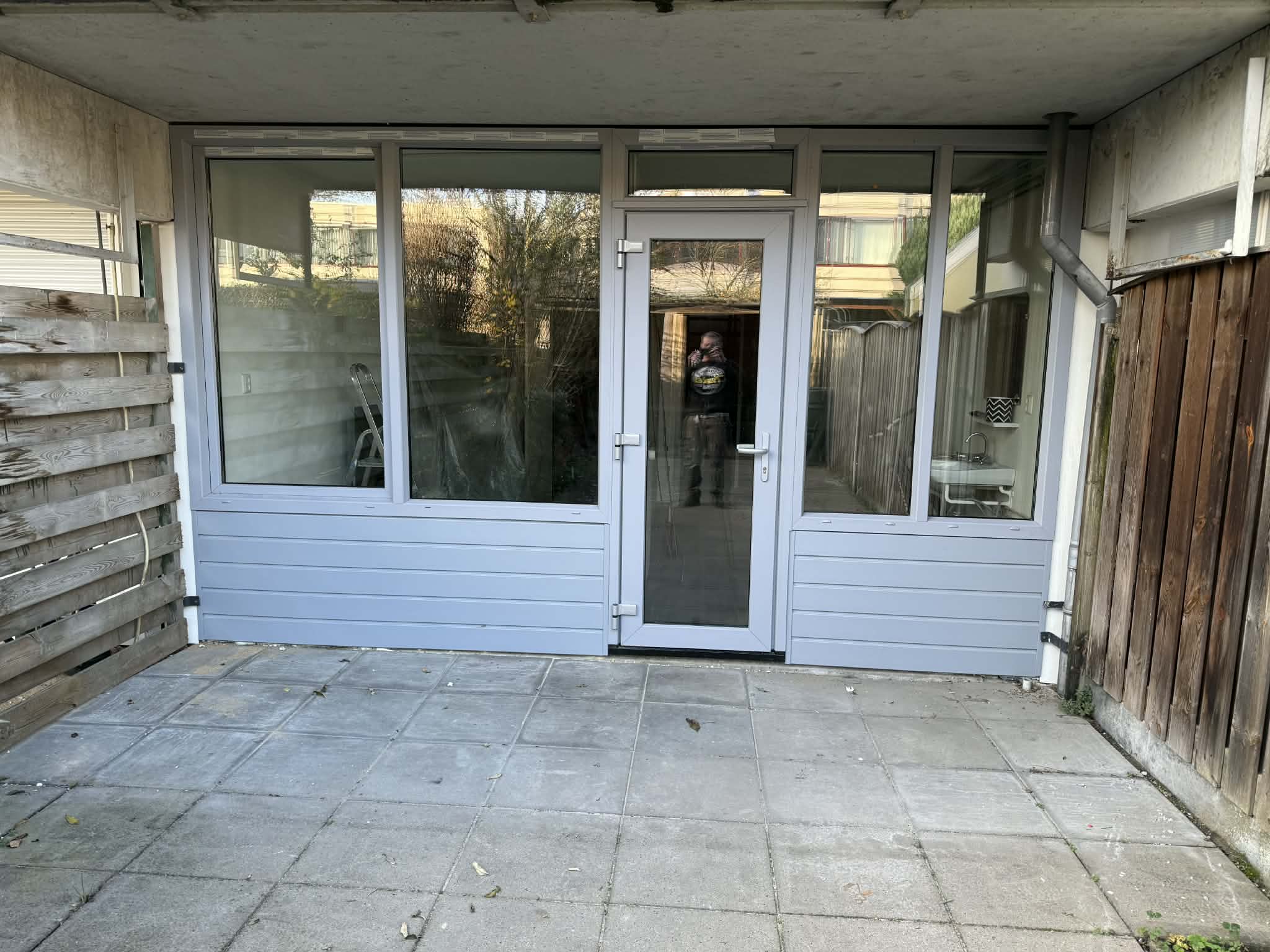 Nieuwe grijze kozijnen met deur aan een terras